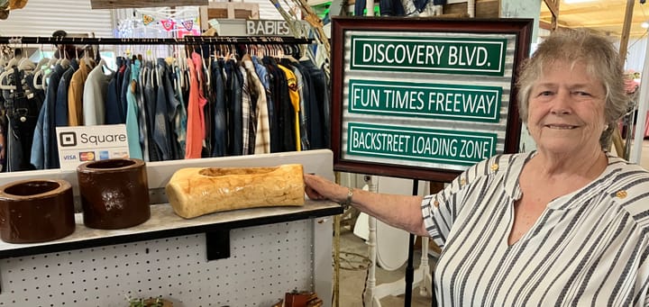 A woman in an arts and crafts booth at a farmers market.