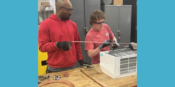 Two HVAC students work on a unit.